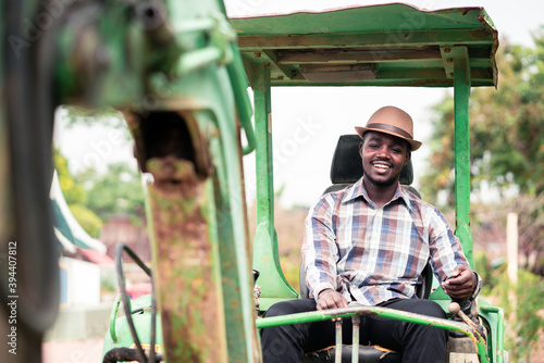 African worker driving heavy construction equipment backhoe with smile and happy
