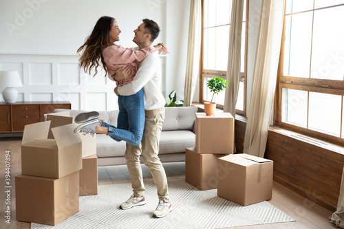 Cuadro en lienzo Happy couple arrive at bought house, cheerful husband lifts up on hands beloved wife family begin new life at first dwelling