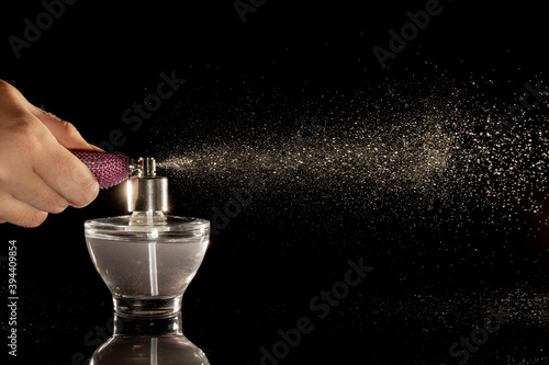 Spraying perfume bottle glass on a black background