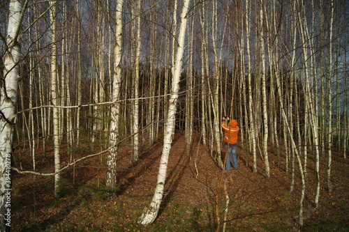 Fototapeta Naklejka Na Ścianę i Meble -  Osoba w pomarańczowej kurtce fotografuje las