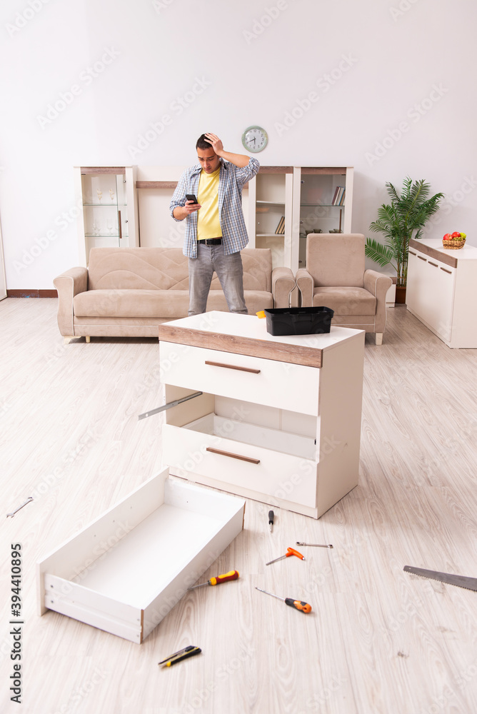 Fototapeta premium Young male carpenter repairing furniture at home