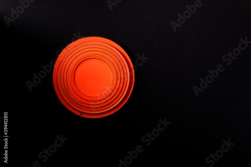 Clay disc target for skeet shooting against the black background. Half lit effect. Copy space