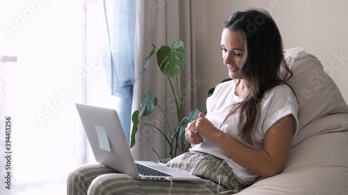 Young woman wears headset conference calling on laptop talks with online teacher studying, working from home. Lady student learning using computer webcam chat makes notes. Distance education concept