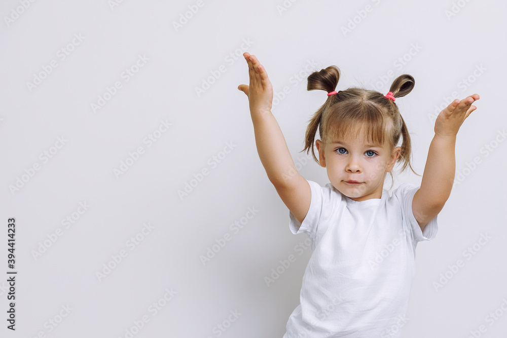 emotional little girl on a light flat background. the child raised his hands up inviting the viewer. layout for design with place for text emotional little girl on a light flat background. the child raised his hands up inviting the viewer. layout for design with place for text