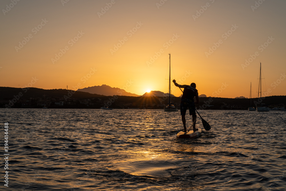 silhouette of a stand up paddle boarder at sunset