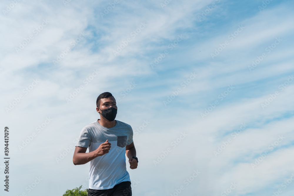 A young African-American athlete in sportswear and a medical mask running around the mountain in the morning A young African-American athlete in sportswear and a medical mask running around the mountain in the morning