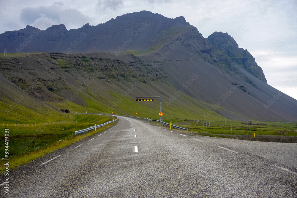 Naklejka premium winding empty road to the tunnel, nature of Iceland