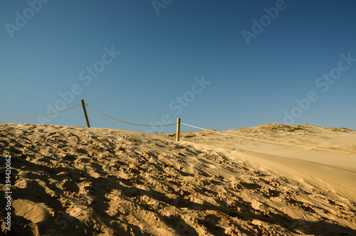 Krajobraz pustynny błękitne niebo piaski z drewnianymi barierkami i śladami na piasku