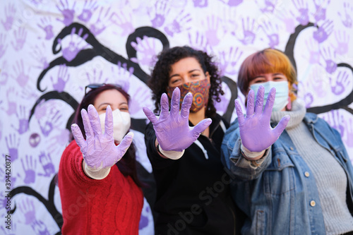 Obraz na plátne Three women with their hands painted purple participating in the International Day for the Elimination of Violence against Women participatory mural