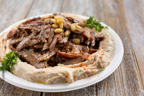 A view of a plate of hummus, topped with beef shawarma.