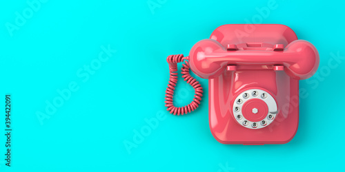 Pink vintage rotary telephone on mint green background.