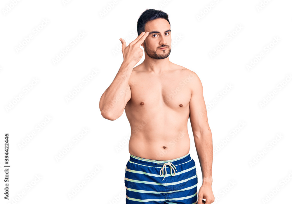Fototapeta premium Young handsome man wearing swimwear shooting and killing oneself pointing hand and fingers to head like gun, suicide gesture.