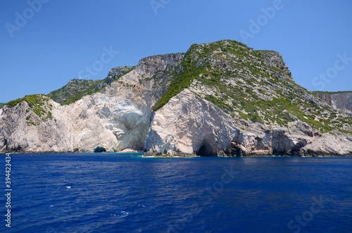 Limestone rocks on the coast of Zakynthos island  Greece. Sunny day  crystal clear water  blue sky  boat trip  rocks falling steeply into the sea.