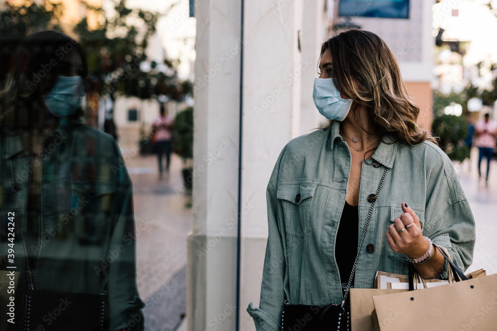 Φωτογραφία portrait of a white woman looking at a store window with many shopping bags