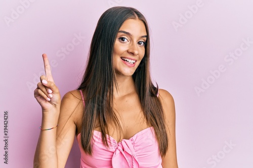 Young hispanic woman wearing casual style with sleeveless shirt pointing finger up with successful idea. exited and happy. number one.