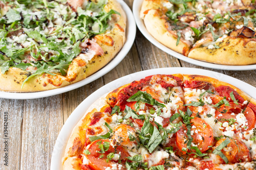 A view of several rustic pizzas on a wooden table surface.