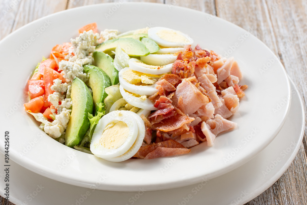 A view of a plate of cobb salad, in a restaurant or kitchen setting. A view of a plate of cobb salad, in a restaurant or kitchen setting.