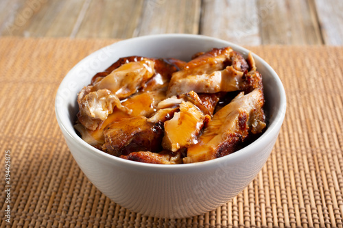 A view of a bowl of teriyaki chicken, in a restaurant or kitchen setting.