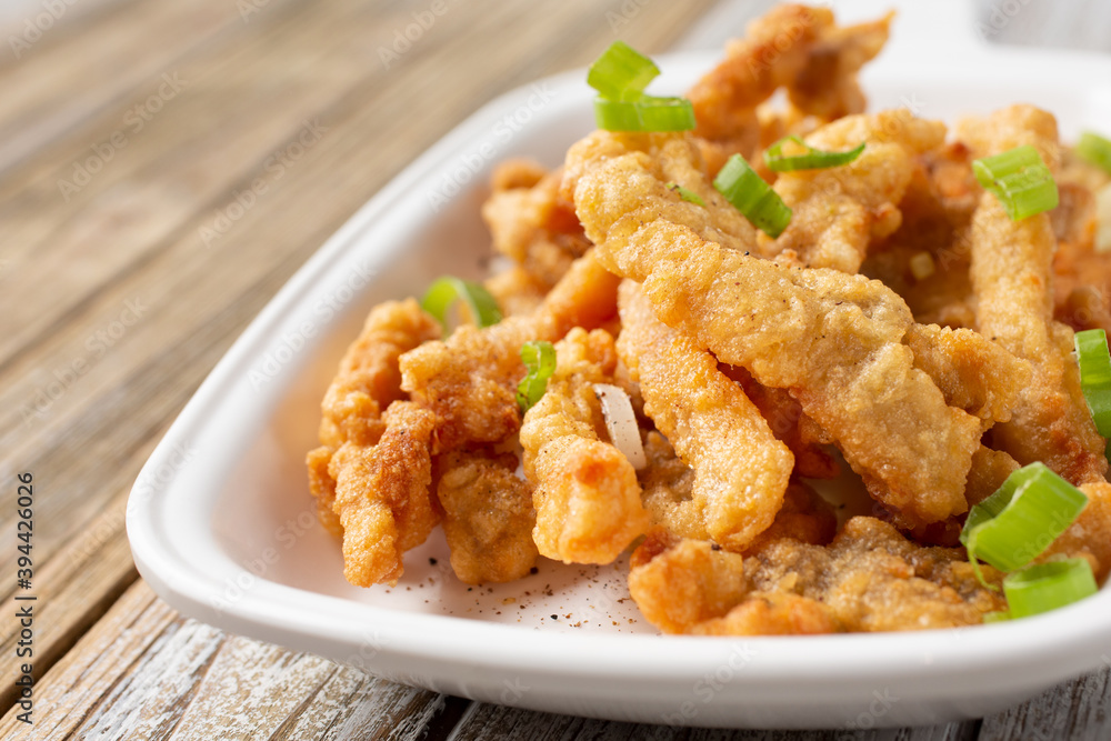 A closeup view of a plate of deep fried pork, in a restaurant or kitchen setting. A closeup view of a plate of deep fried pork, in a restaurant or kitchen setting.