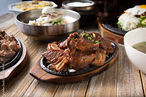 фотографія A view of several Korean entrees prepared on a wooden table surface, featuring galbi
