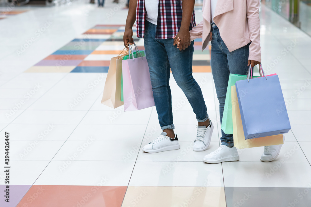 Fototapeta premium Unrecognizable African Couple Walking In Mall, Carrying Bright Shopping Bags, Cropped Image