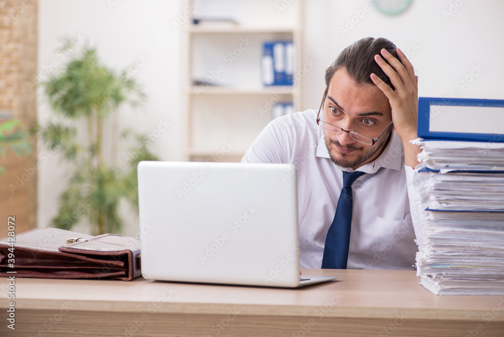 Young businessman unhappy with excessive work in the office Young businessman unhappy with excessive work in the office