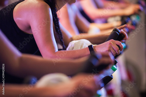 Sweaty torso of caucasian woman on a stationary bike in a line of other riders at a group spin class
