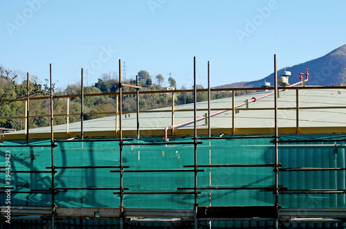 Una cisterna industriale completamente rivestita di impalcature e ponteggi per lavori di ristrutturazione.  photo