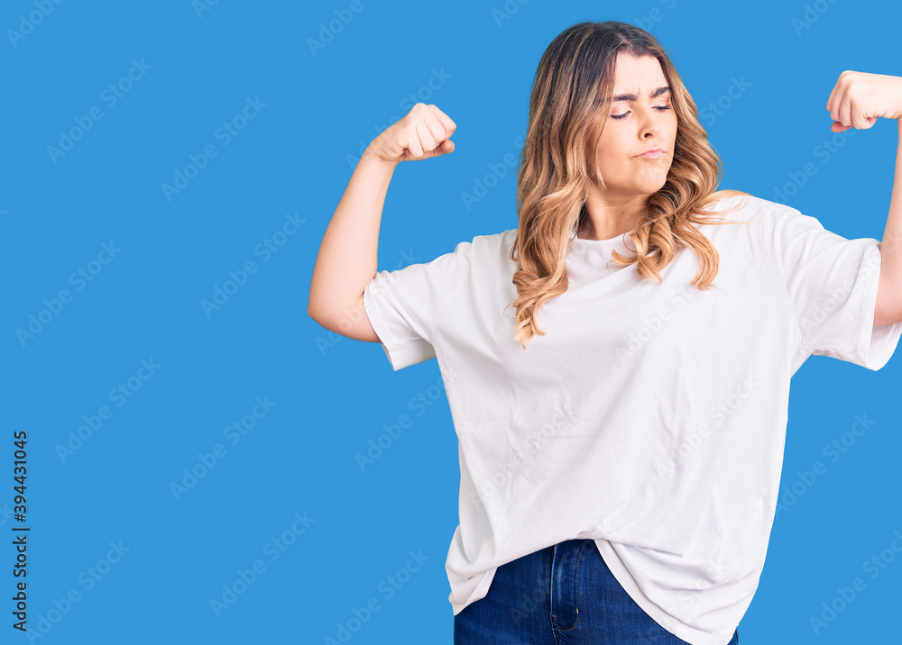 Fototapeta premium Young caucasian woman wearing casual clothes showing arms muscles smiling proud. fitness concept.