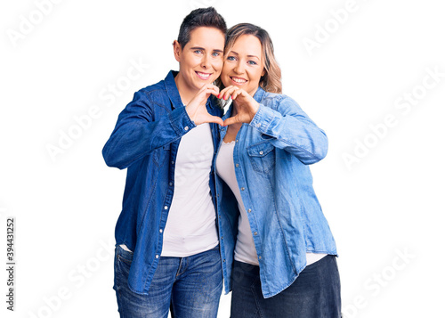 Couple of women wearing casual clothes smiling in love doing heart symbol shape with hands. romantic concept.