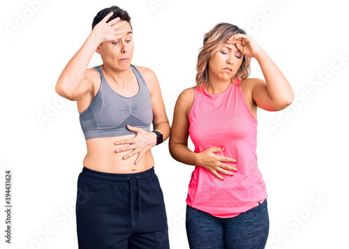 Couple of women wearing sportswear touching forehead for illness and fever, flu and cold, virus sick