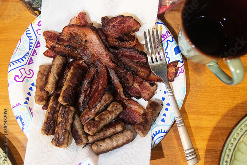 Plate piled high with bacon and sausage for breakfast photo