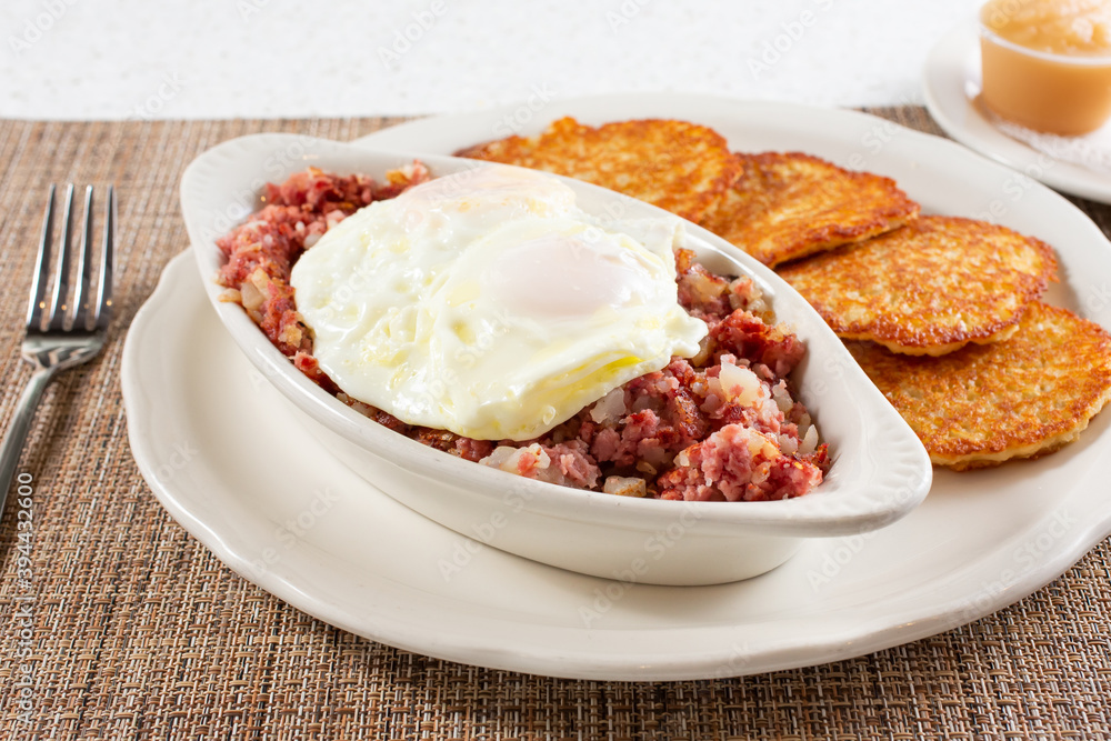 A view of a casserole dish of corned beef hash, topped with a over easy eggs. A view of a casserole dish of corned beef hash, topped with a over easy eggs.