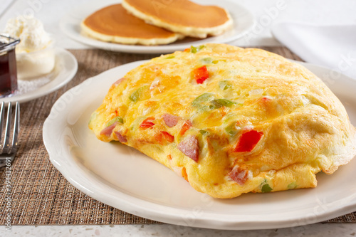 A view of a baked western omelet, with a side of pancakes.