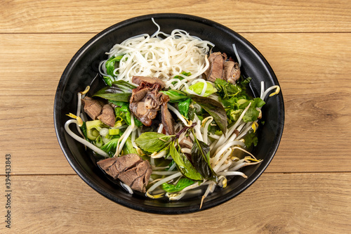 Chinese beef vegetable and rice noodle soup in a black bowl