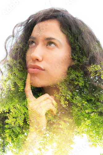 A doulbe exposure portrait of a thoughtful young woman with curly hair and green fern photo