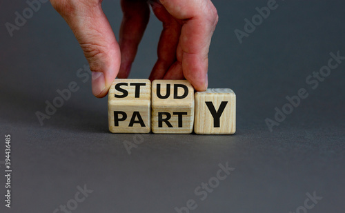 Study or party. Male hand flips wooden cubes and changes the word 'study' to 'party' or vice versa. Beautiful grey background, copy space. Study or party concept.