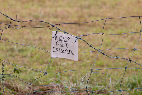 Keep out, private sign fixed to barbed wire fence