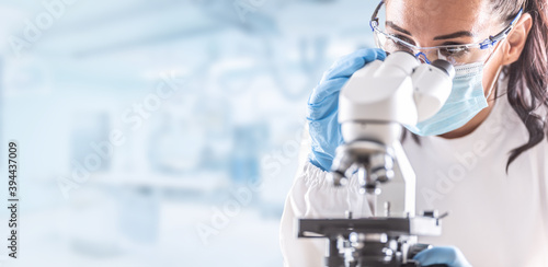 Photo Female lab technician in protective glasses, gloves and face mask sits next to a
