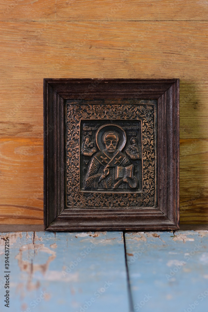 close-up religious image of metal in a frame on a wooden background