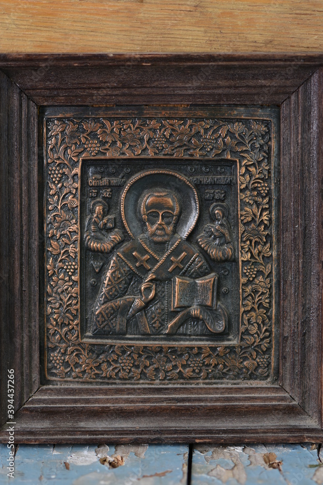 close-up religious image of metal in a frame on a wooden background