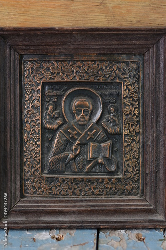 close-up religious image of metal in a frame on a wooden background © Alla Dmitriuk