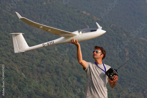 Man in sunglasses is playing with a ero plane glider discus 2c model with remote control in the top of a mountain