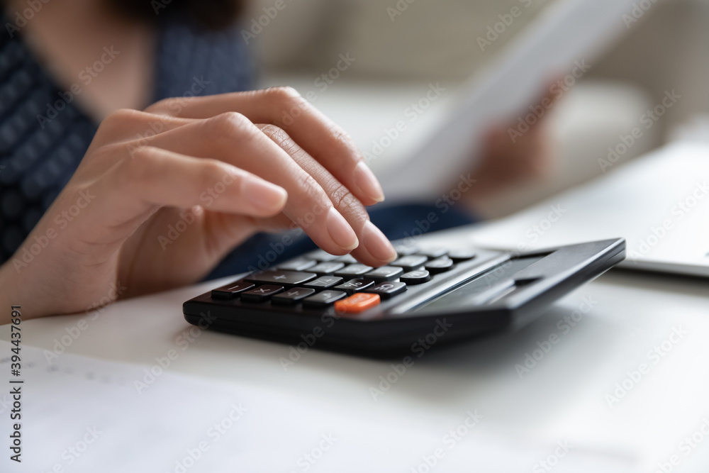 Close cropped up woman using calculator, checking documents and household finances, planning budget, savings for future, female bookkeeper calculating taxes, domestic expenses, paying bills Close cropped up woman using calculator, checking documents and household finances, planning budget, savings for future, female bookkeeper calculating taxes, domestic expenses, paying bills