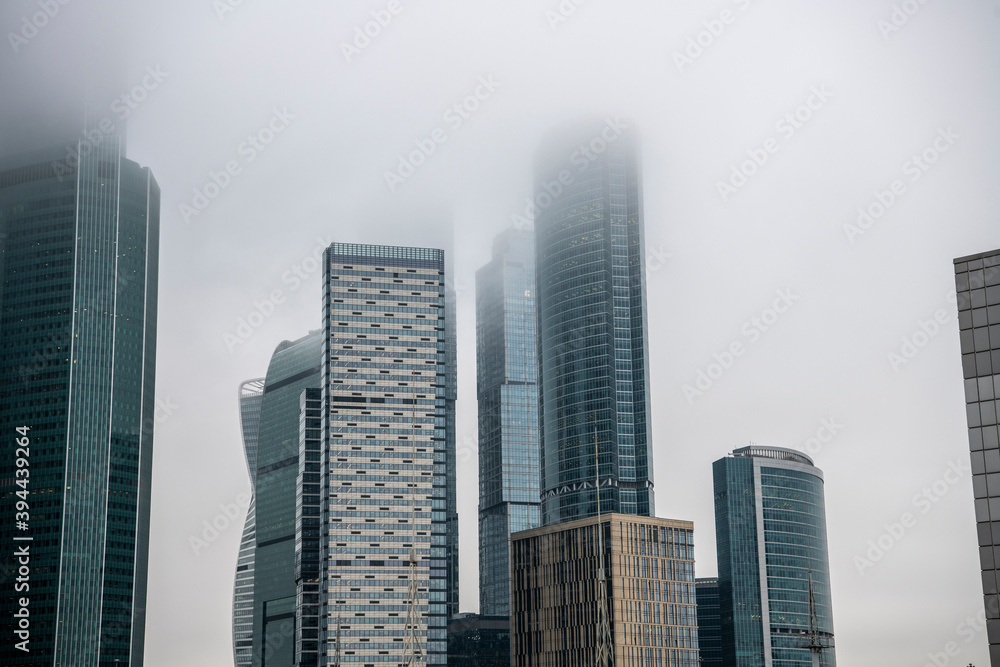 cityscape with high-rise buildings whose upper floors have melted into fog