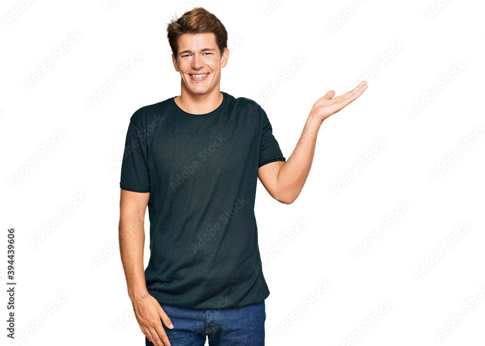 Naklejka premium Handsome caucasian man wearing casual clothes smiling cheerful presenting and pointing with palm of hand looking at the camera.