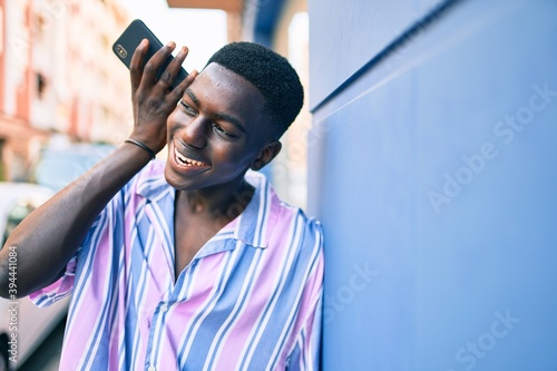 Young african american man smiling happy tallking on the smartphone at street of city. photo