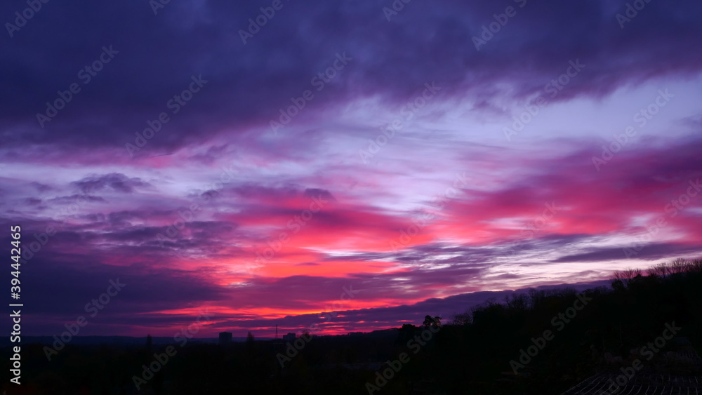 Amazing sunrise in rural scene. Dramatic sky with sunbeam and stratus clouds over the silhouette of hill on the horizon.