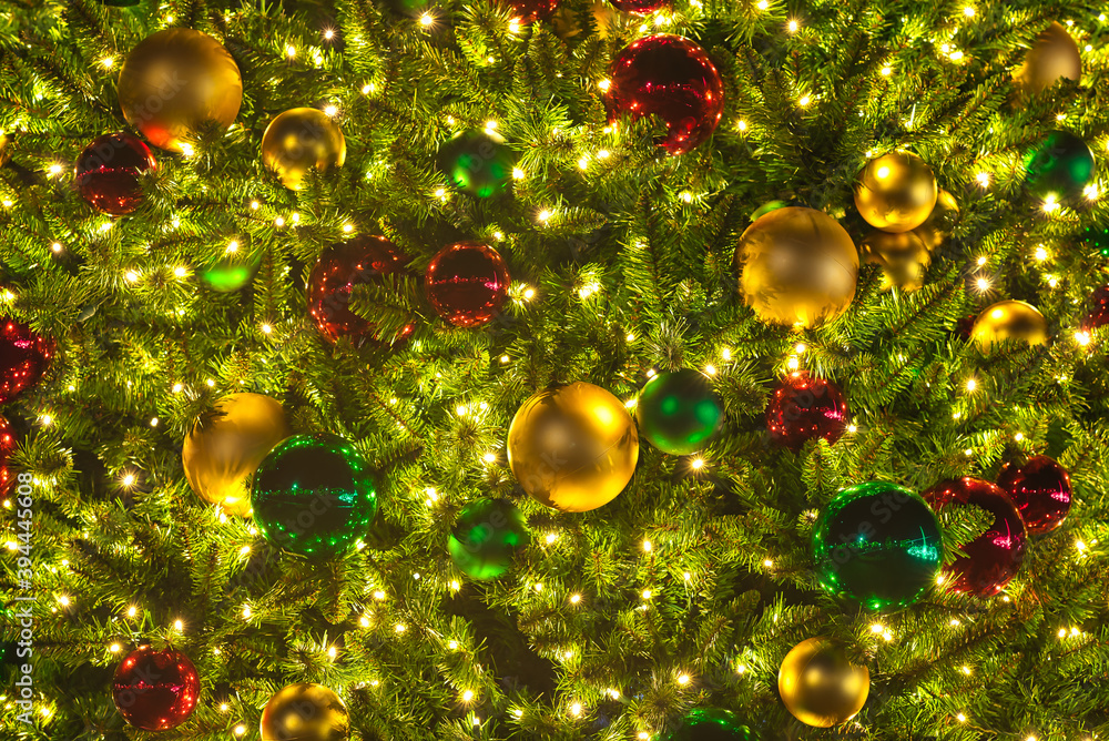 A close up of a Christmas tree with lights and ornaments at night.