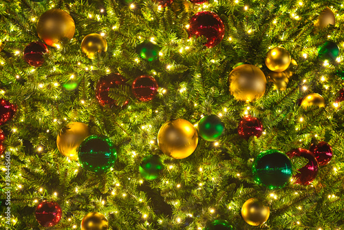 A close up of a Christmas tree with lights and ornaments at night.
